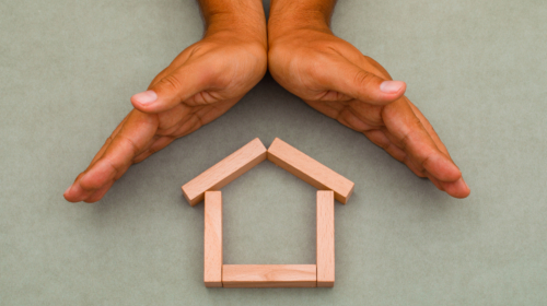 Hands enclosing wooden house1