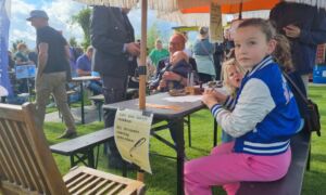 Meisje schrijft kaart voor familie tijdens festival