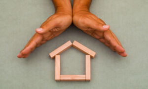 Hands enclosing wooden house1