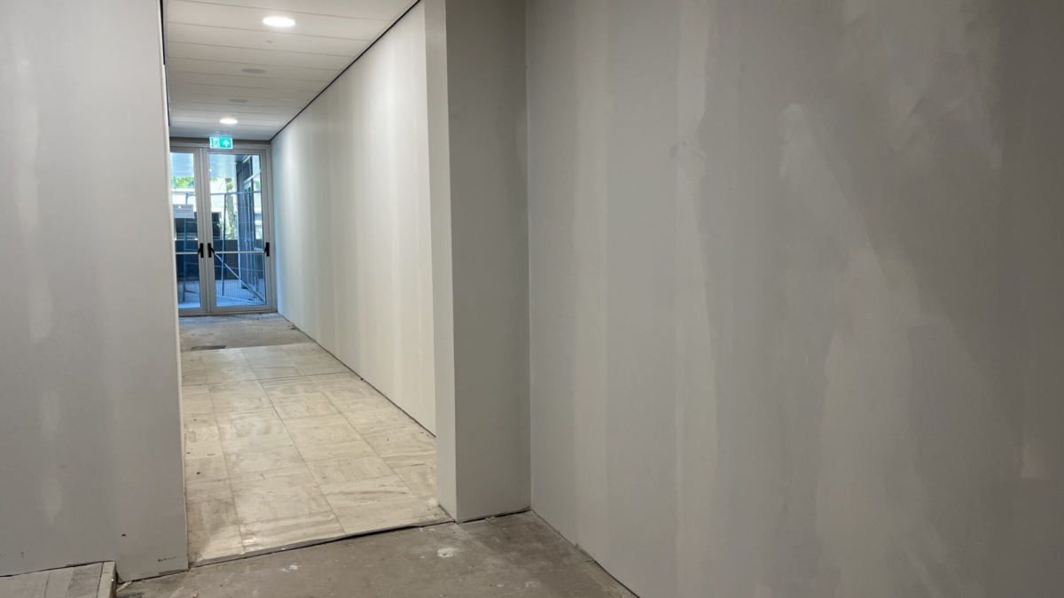 De dikke betonnen muur die de oude raadszaal van het wooncomplex scheidt