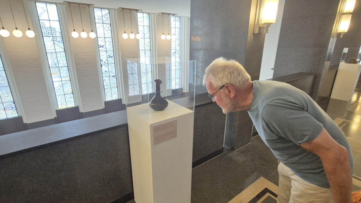 Dick Buursink kijkt naar een vaas uit de Enschedese stadsbrand