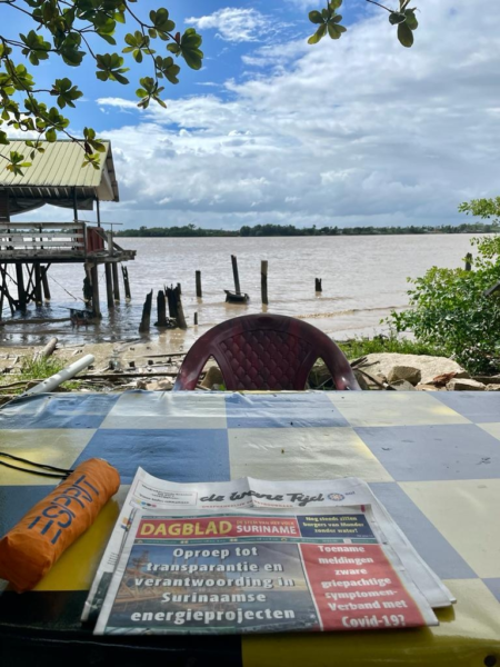 Henk vd Wetering bij Riverside Bar Kitchen favo plek om krant te lezen in Suriname